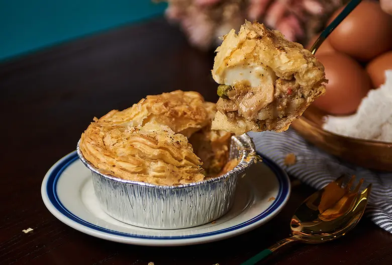 Spoonful of chicken pie cut and scooped up, chunky ingredients inside visible