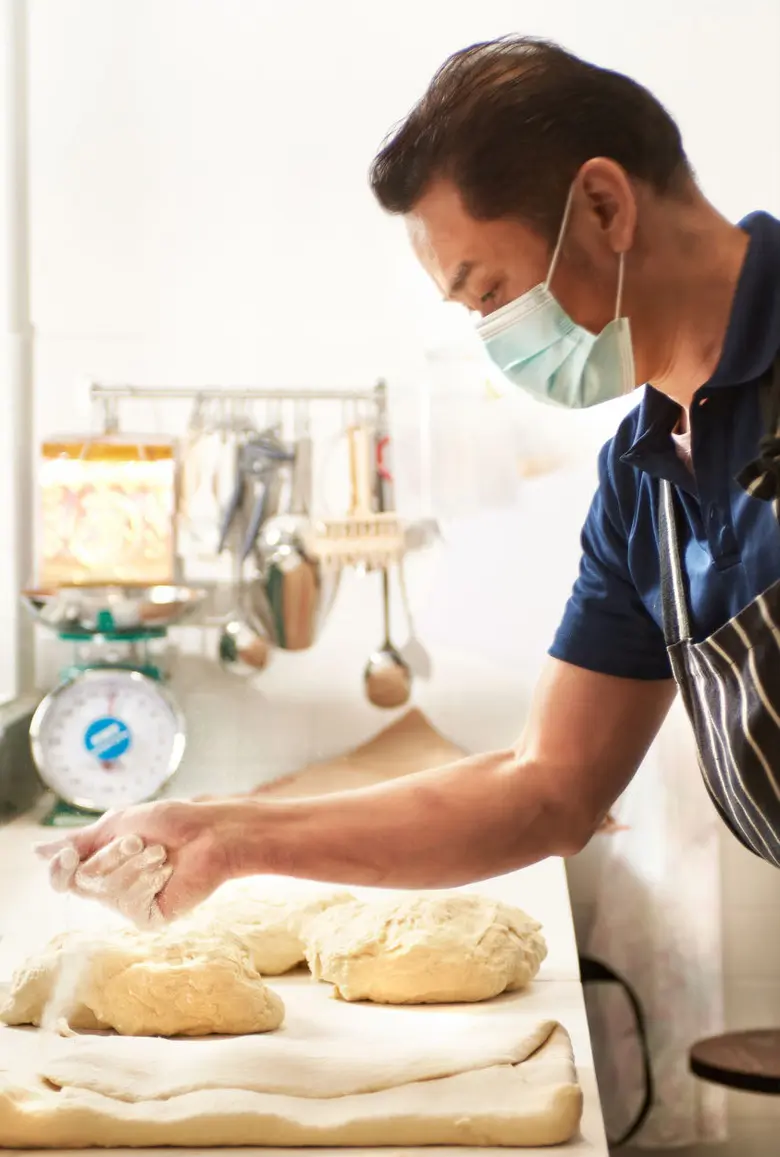 Pastry chef preparing and sprinkling flour onto pastry dough